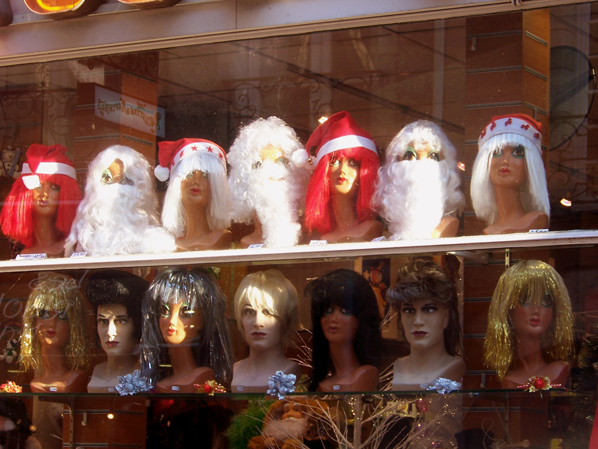 many mannequin heads on display behind glass in shop