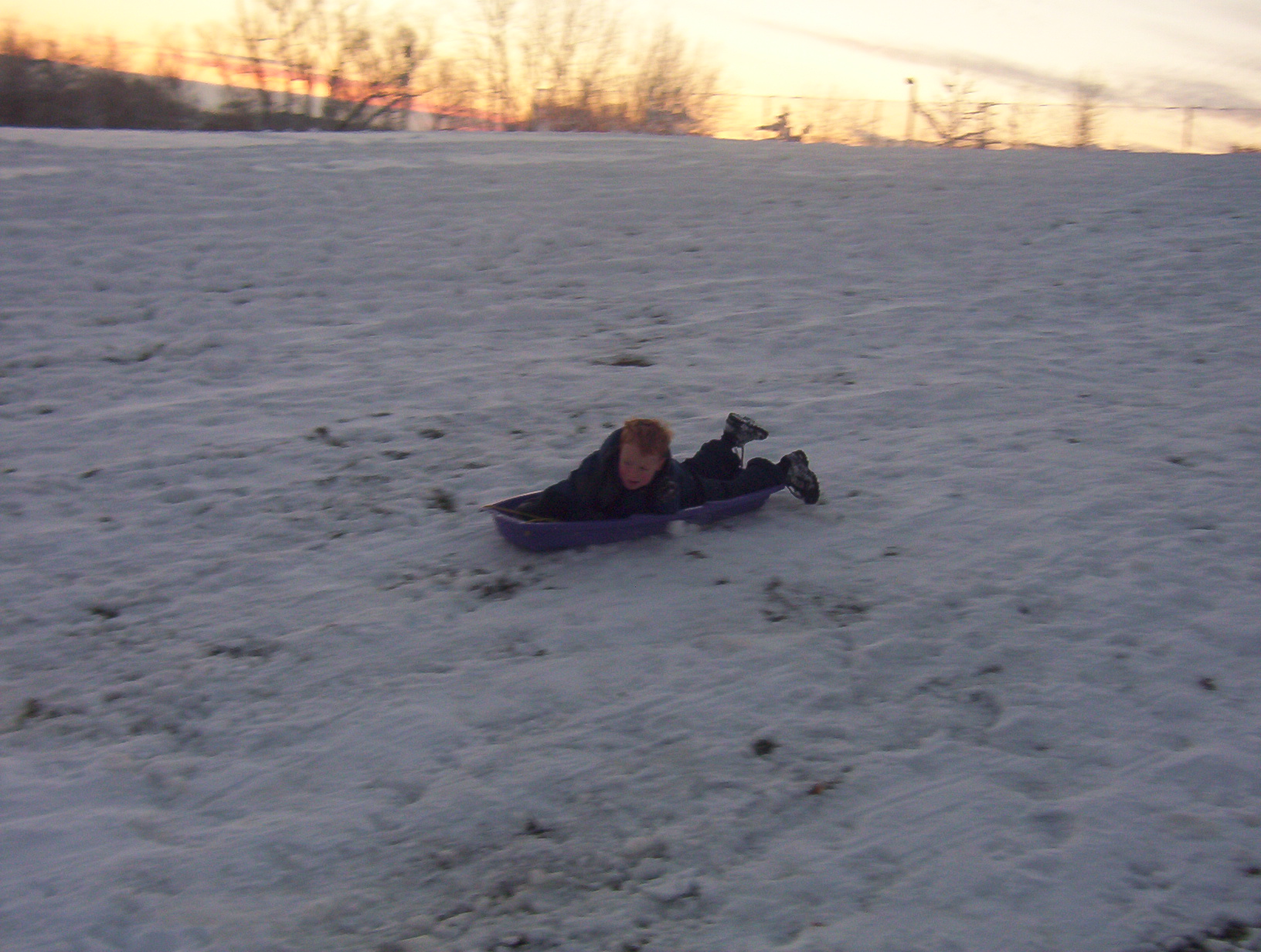 the child is laying on his stomach on a small snow sled