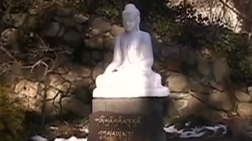 a small statue of a buddha is near some water