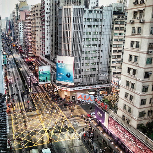 view of a busy city street in the rain with billboards on top