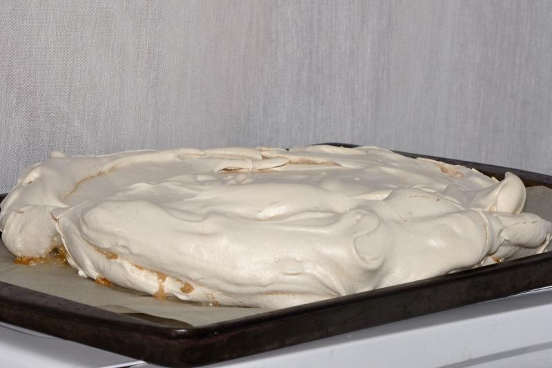 a white frosted cake in a baking pan on top of the oven