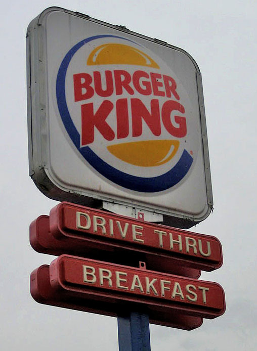 a sign is displayed on a street corner for a burger king restaurant