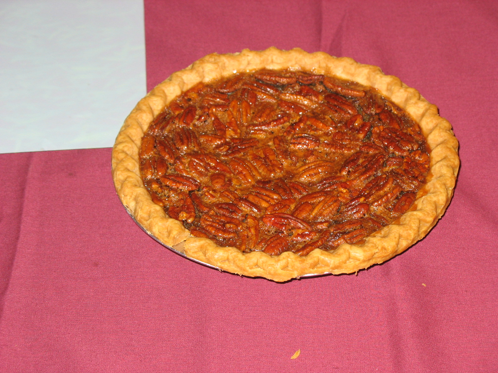 a pecan pie sitting on top of a pink tablecloth