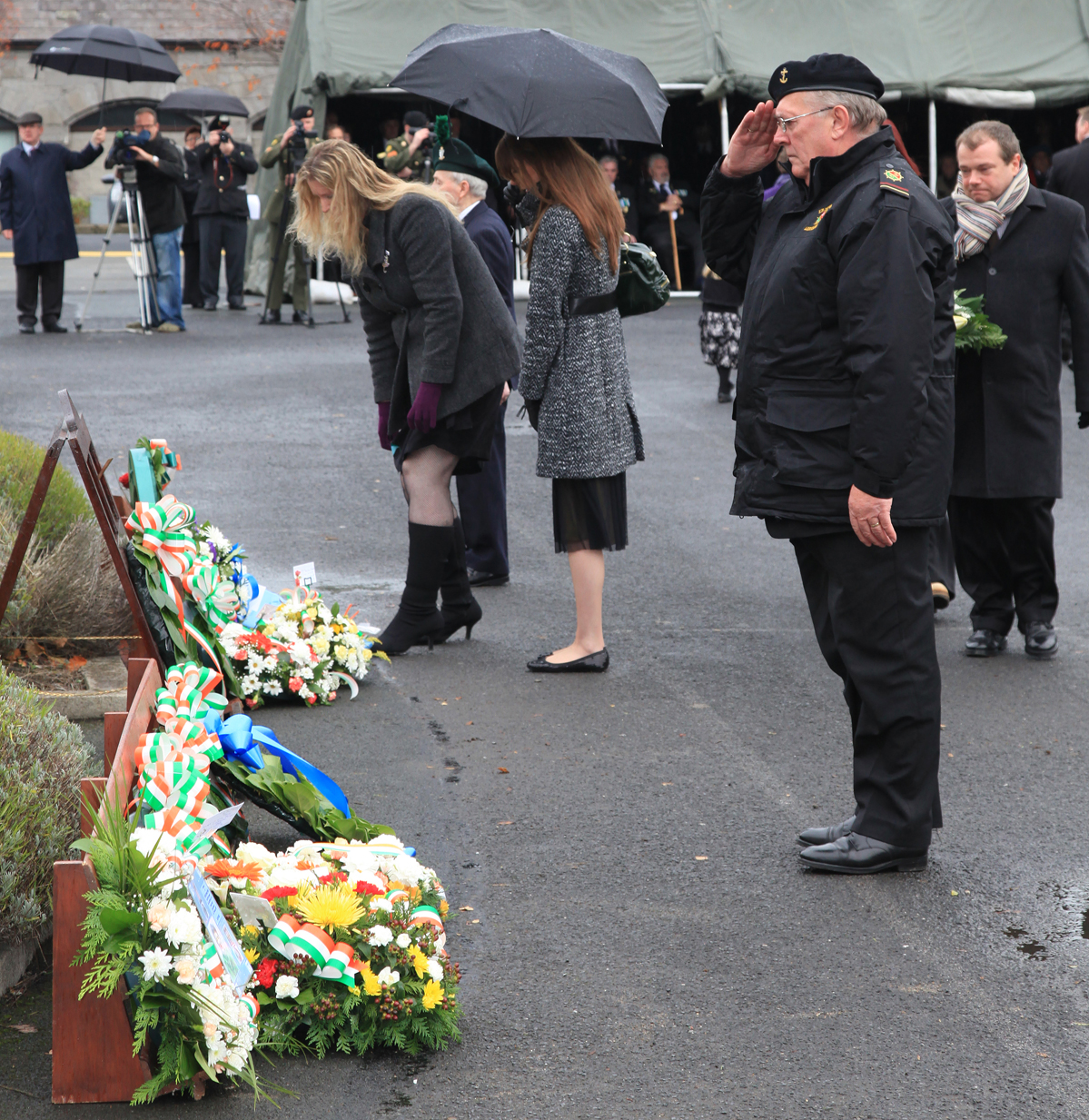 people gather at the memorial laying flowers