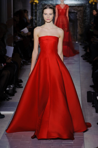 a woman wearing a red dress on the runway