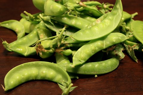 a pile of green peas sitting on top of a wooden surface