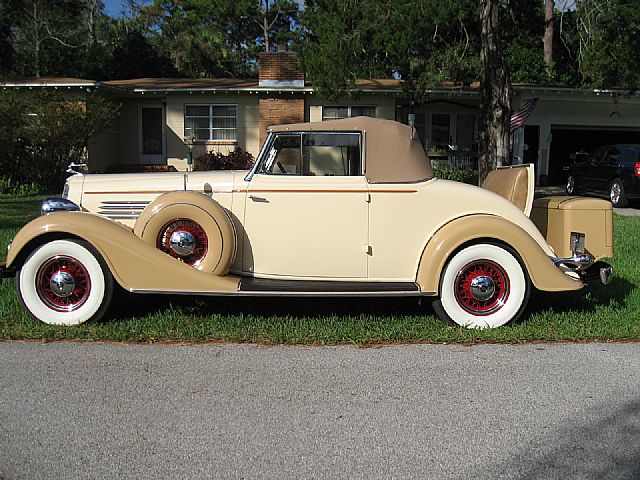 a tan and white vintage car parked on grass