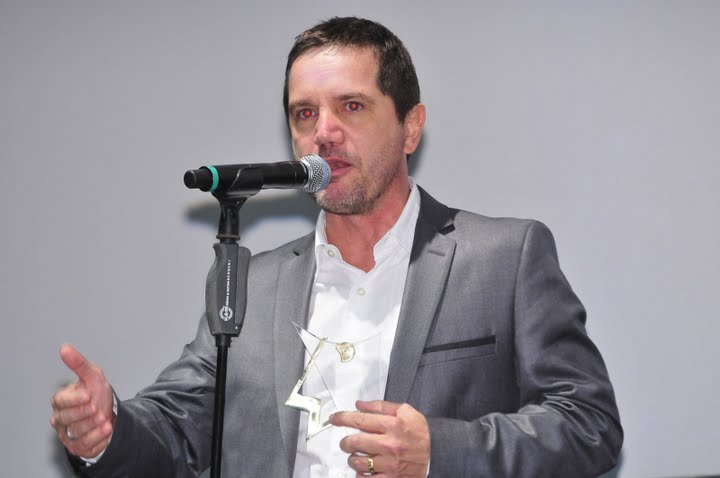 a man in a gray suit is talking into a microphone