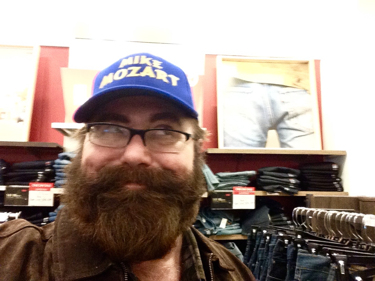 a man wearing a blue hat, glasses and jacket in a clothing store