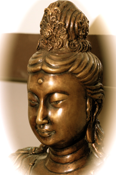 a bronze buddha sculpture with eyes closed on white wall