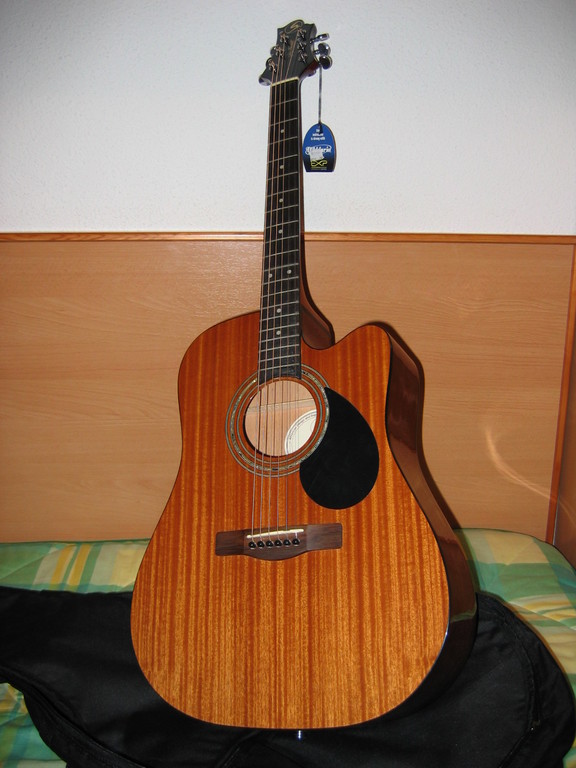 a small wooden guitar sits on top of a bag