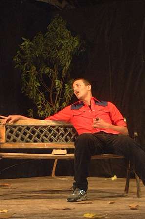 two men sitting on a bench together on stage