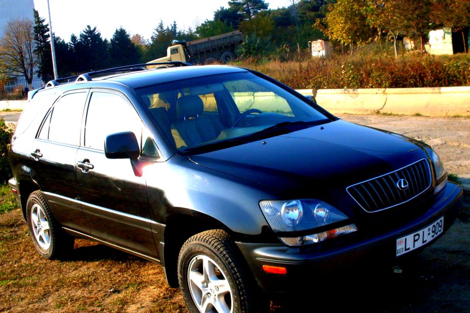 a large black suv with a white top parked on a field