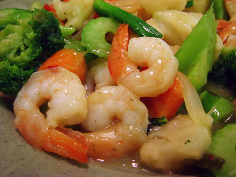 shrimp, vegetables and broccoli sit on a plate