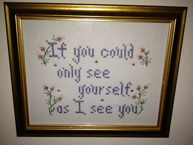 a picture with a cross stitch quote hanging in a frame
