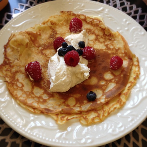 pancakes with fruit and cream on white plate