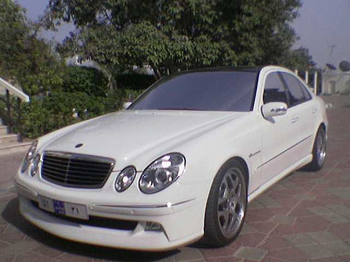 white mercedes s - class parked in front of some trees