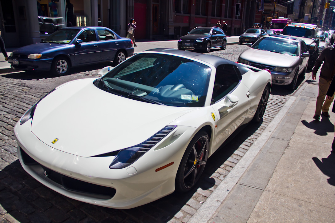 a white sports car parked on the side of a city street