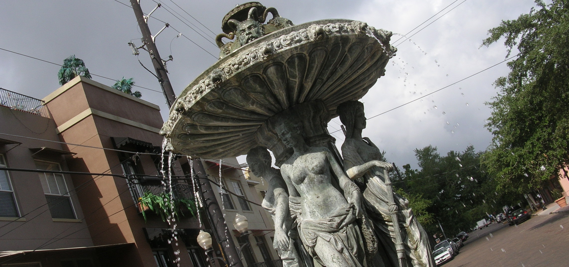 a fountain with three statues of women holding umbrellas on it's sides