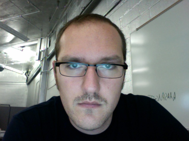 a man with glasses and mustache and a black shirt