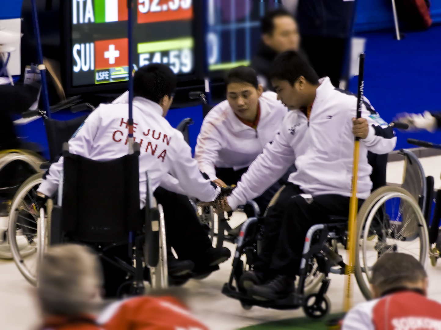 three men in wheel chairs holding onto a pole