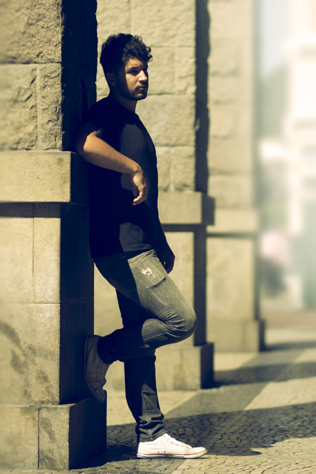 a young man leans against a wall on the street