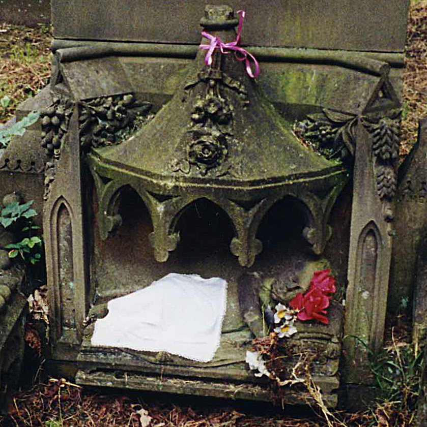 a small monument in a cemetery with a pink ribbon
