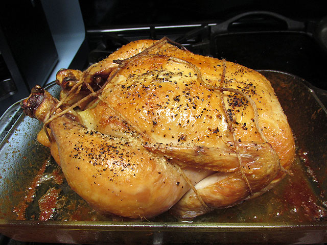 roasting a chicken in an oven with spices and pepper on the top