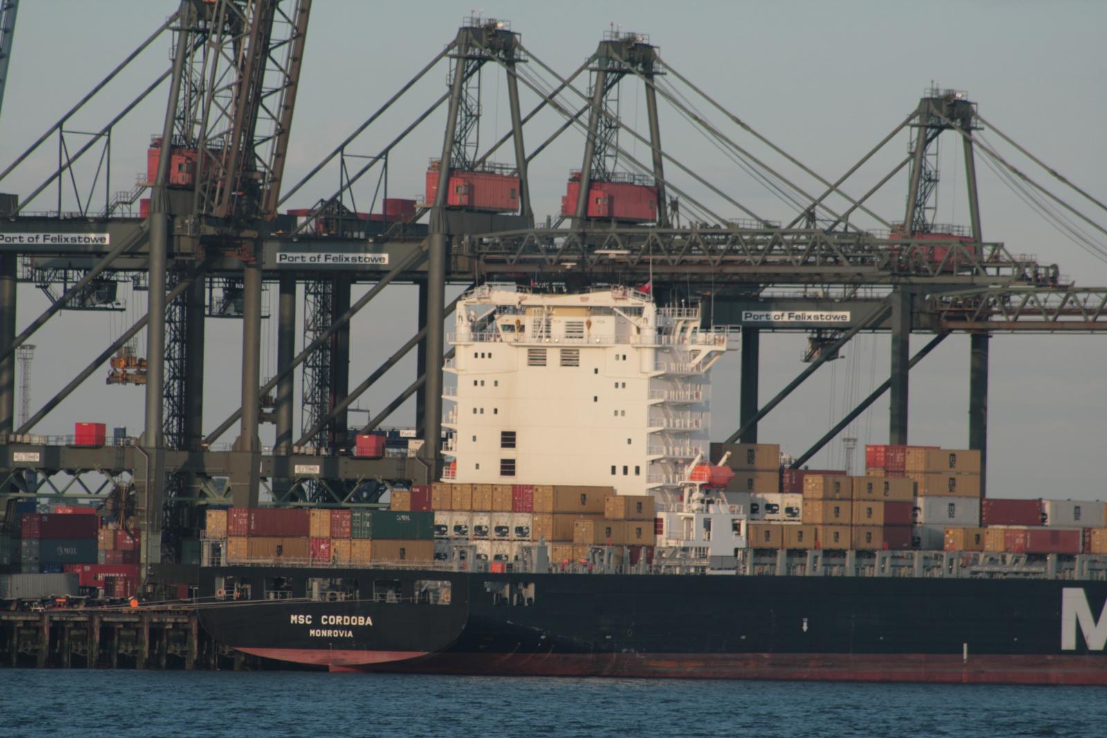 cargo ship anchored in large container harbor with cranes