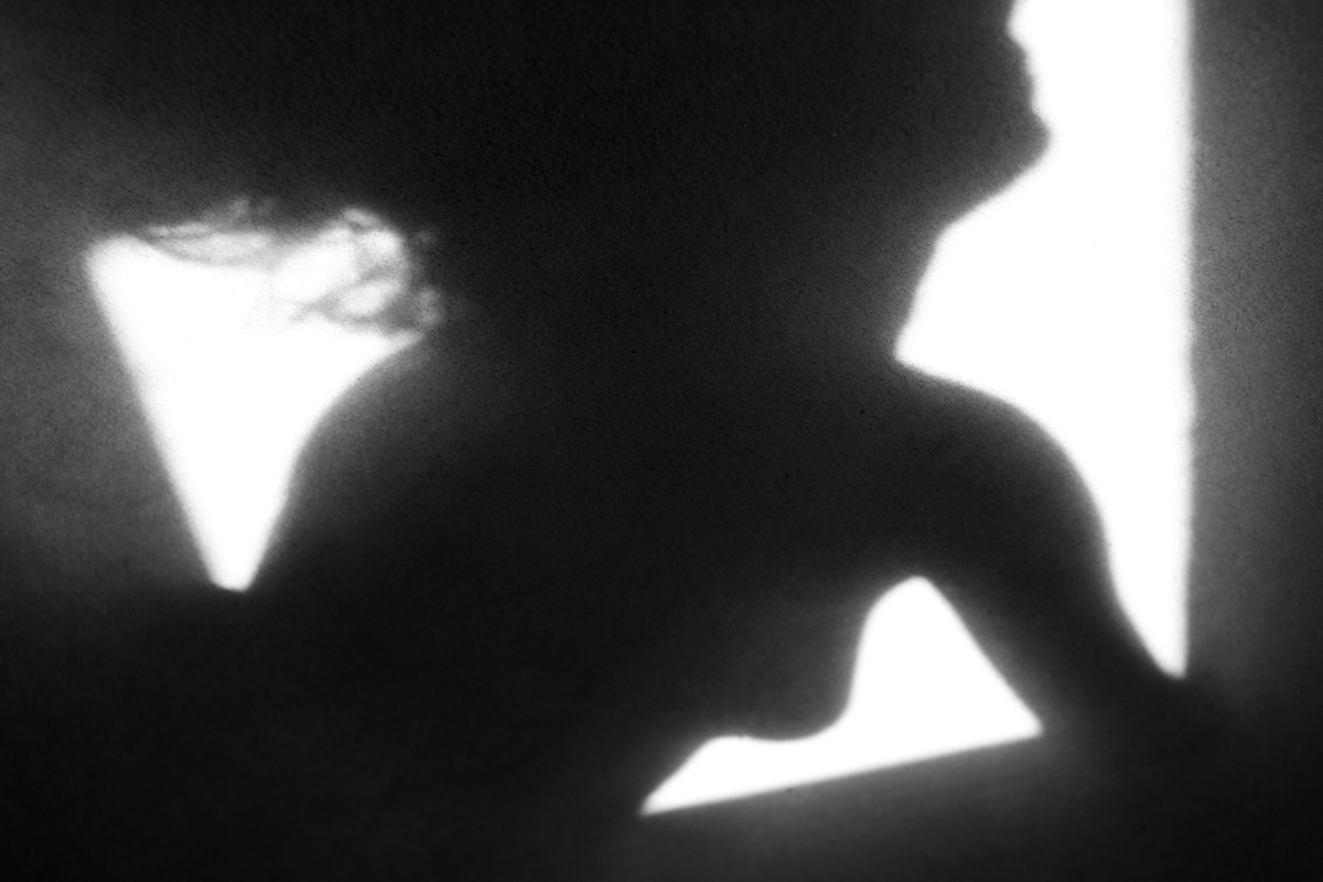 silhouette of a young woman on a window ledge