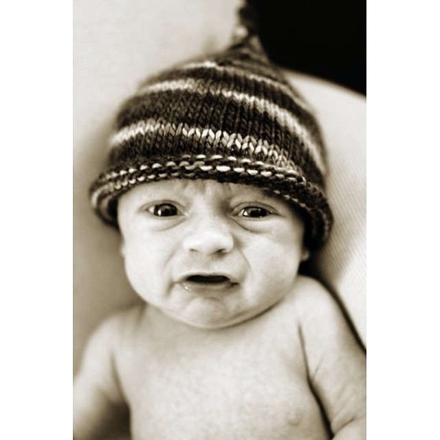 a black and white image of a baby in a knit hat