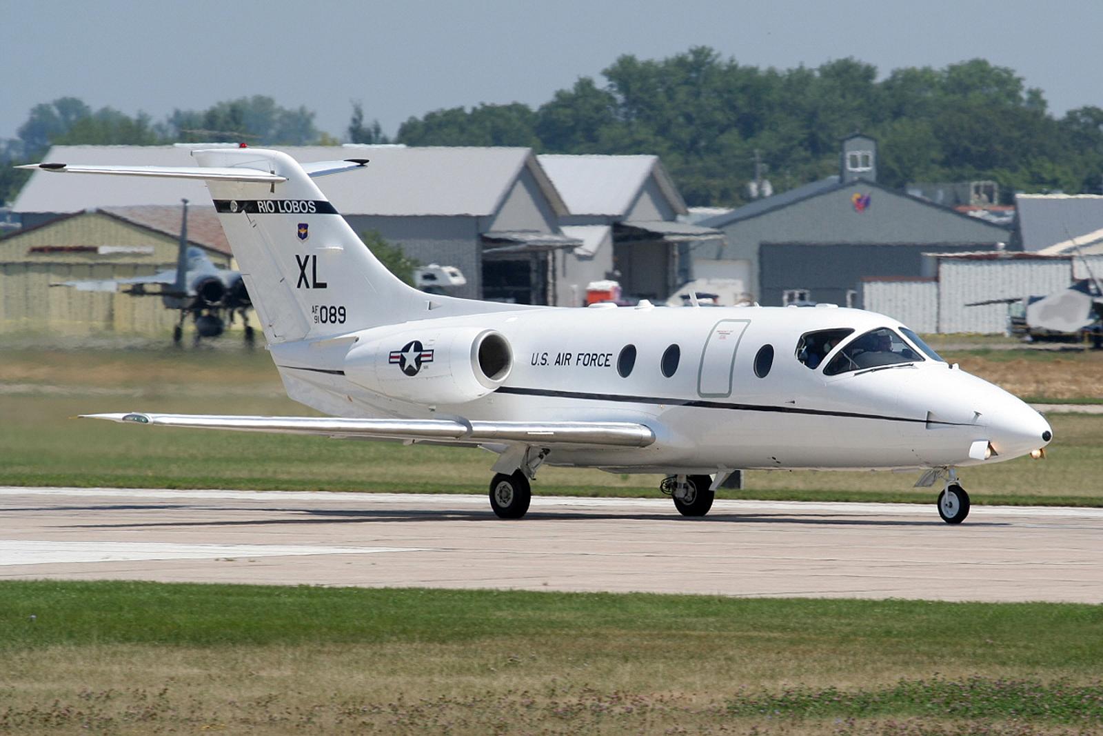 small white plane parked on a landing strip in a large field of grass