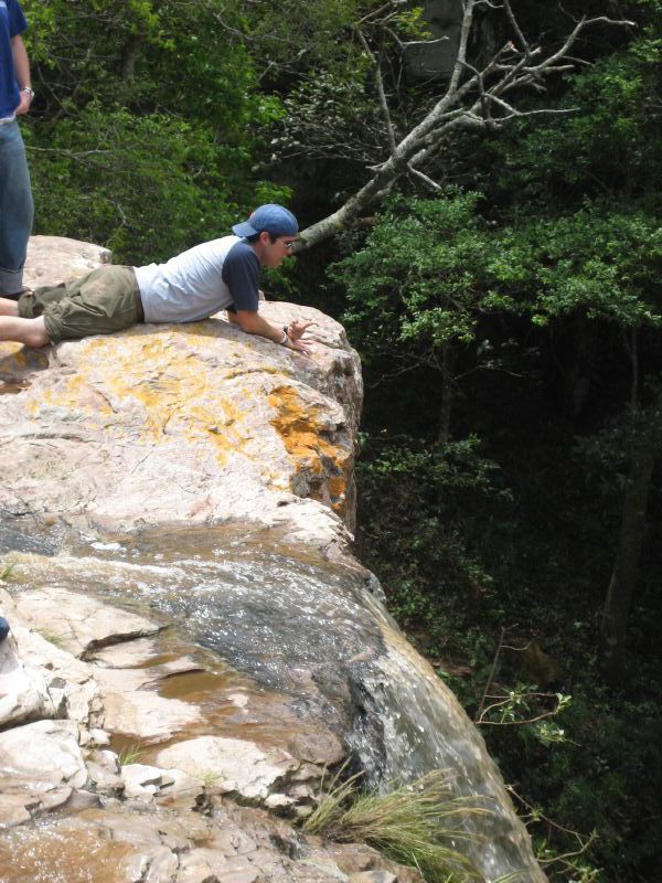 two men on the side of a cliff, reaching into the air