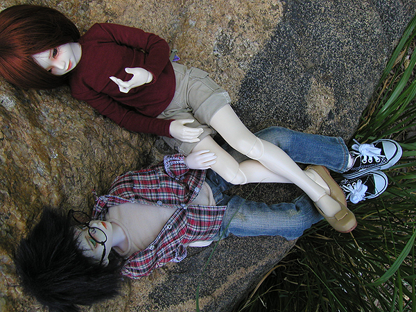 a couple of dolls that are laying on a cement surface