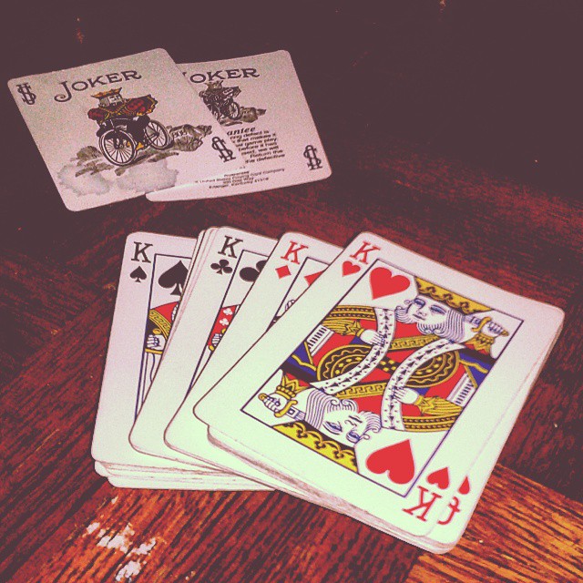 four playing cards, one in the foreground and two in the background on a table