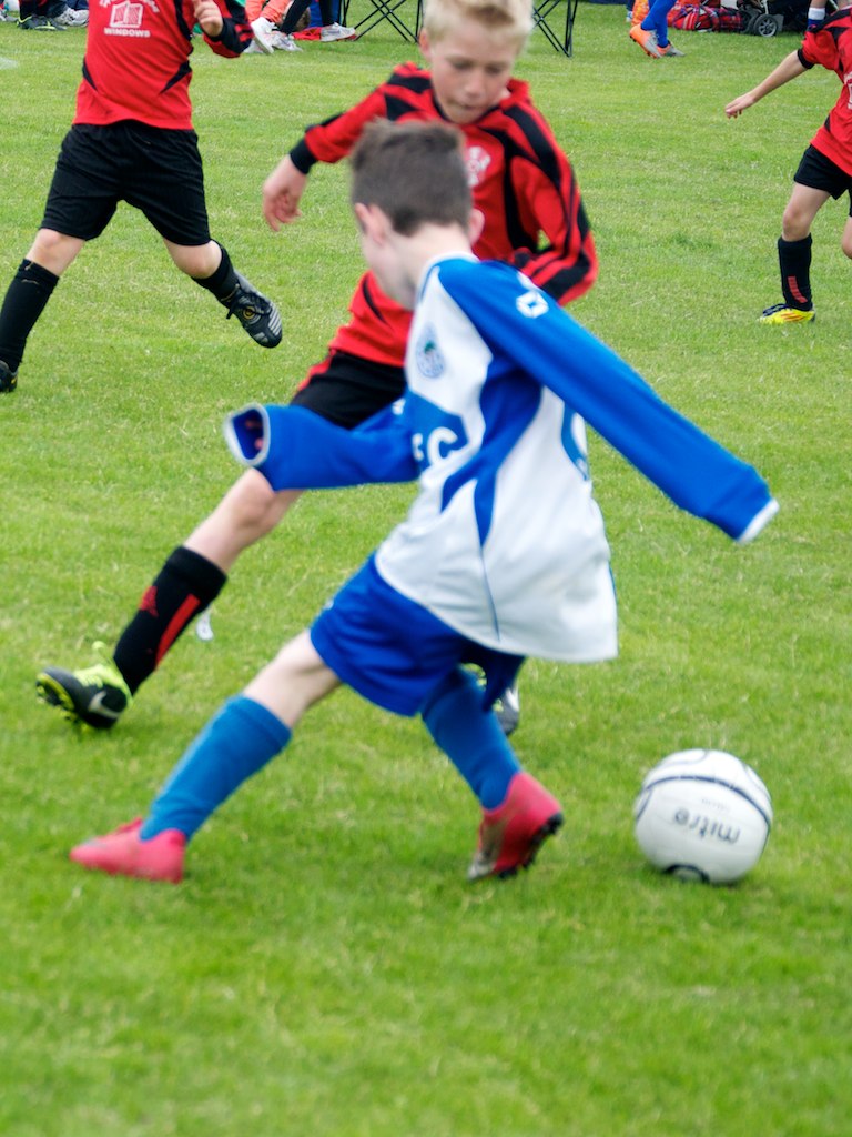 some children playing soccer on a field with grass