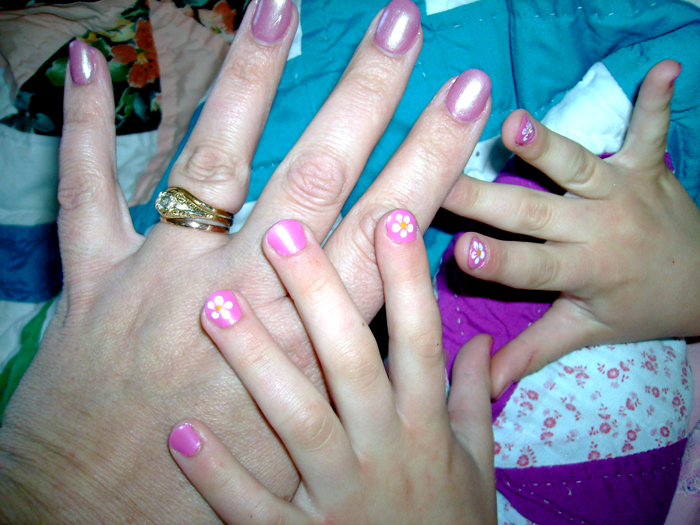 woman with pink and white nail polish has flowers on her fingers