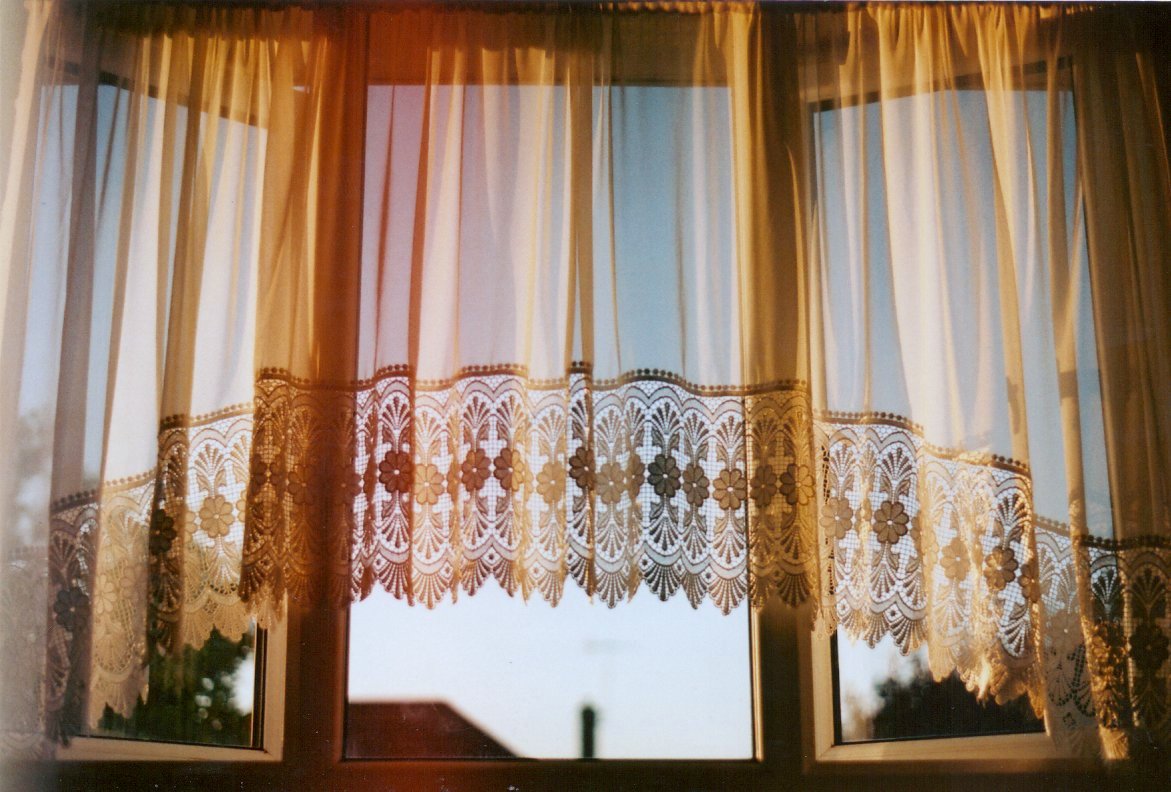 the curtain with white lace over it is hanging