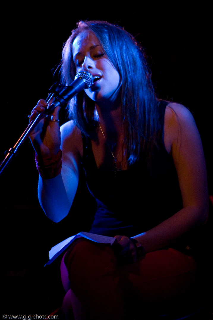 a woman in a black top is sitting and playing a flute