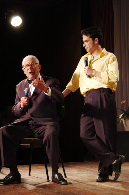 two men talking on stage one with a microphone