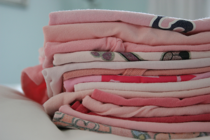 a stack of folded t - shirts on the bed
