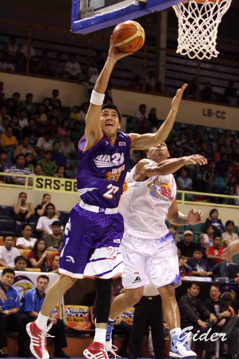 two basketball players fighting for a ball inside of a gym