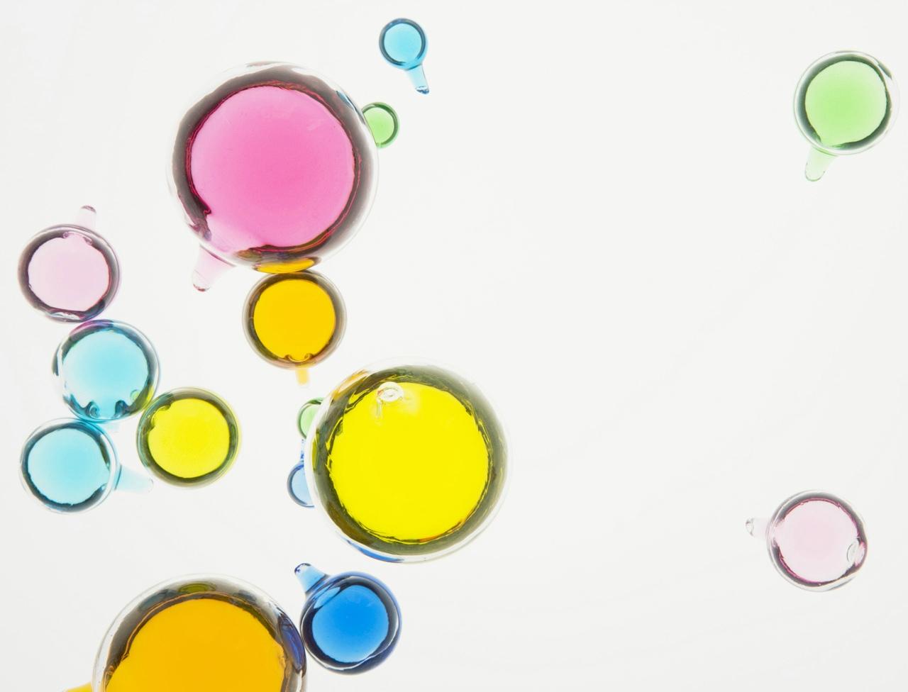 drops of colored bubbles floating on top of white surface