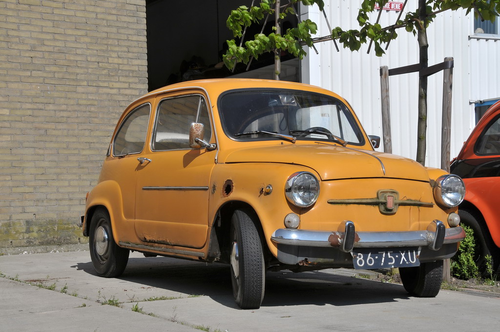 a small yellow car parked next to an orange car