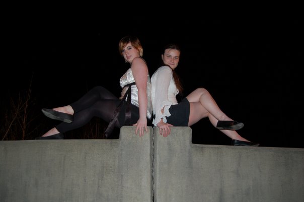 two girls sitting on a concrete wall