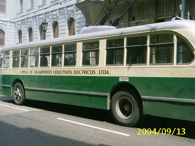 an old green bus parked in front of a large white building