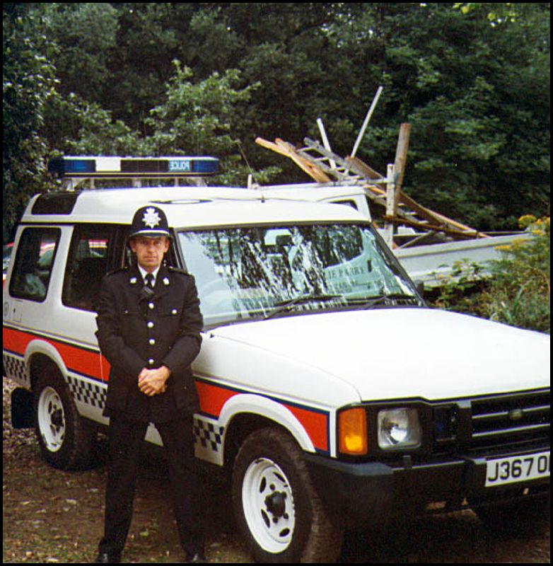 a cop stands in front of his patrol vehicle and tree limbs
