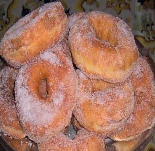 a bowl filled with sugar covered donuts on top of a table
