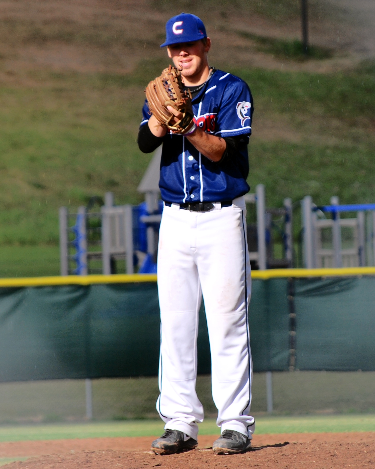 a baseball player wearing a blue and white uniform, standing on the pitchers mound