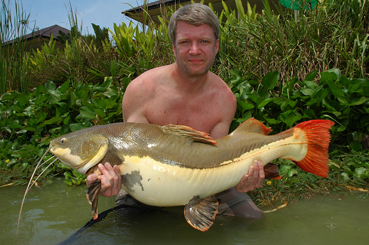 man holding a big fish while sitting in the water